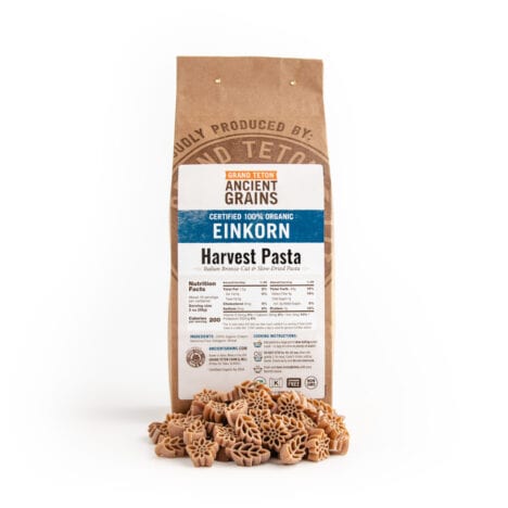Grand Teton Ancient Grains organic einkorn Harvest Pasta in a kraft paper bag with sunflower-shaped and einkorn wheat-shaped pasta in front